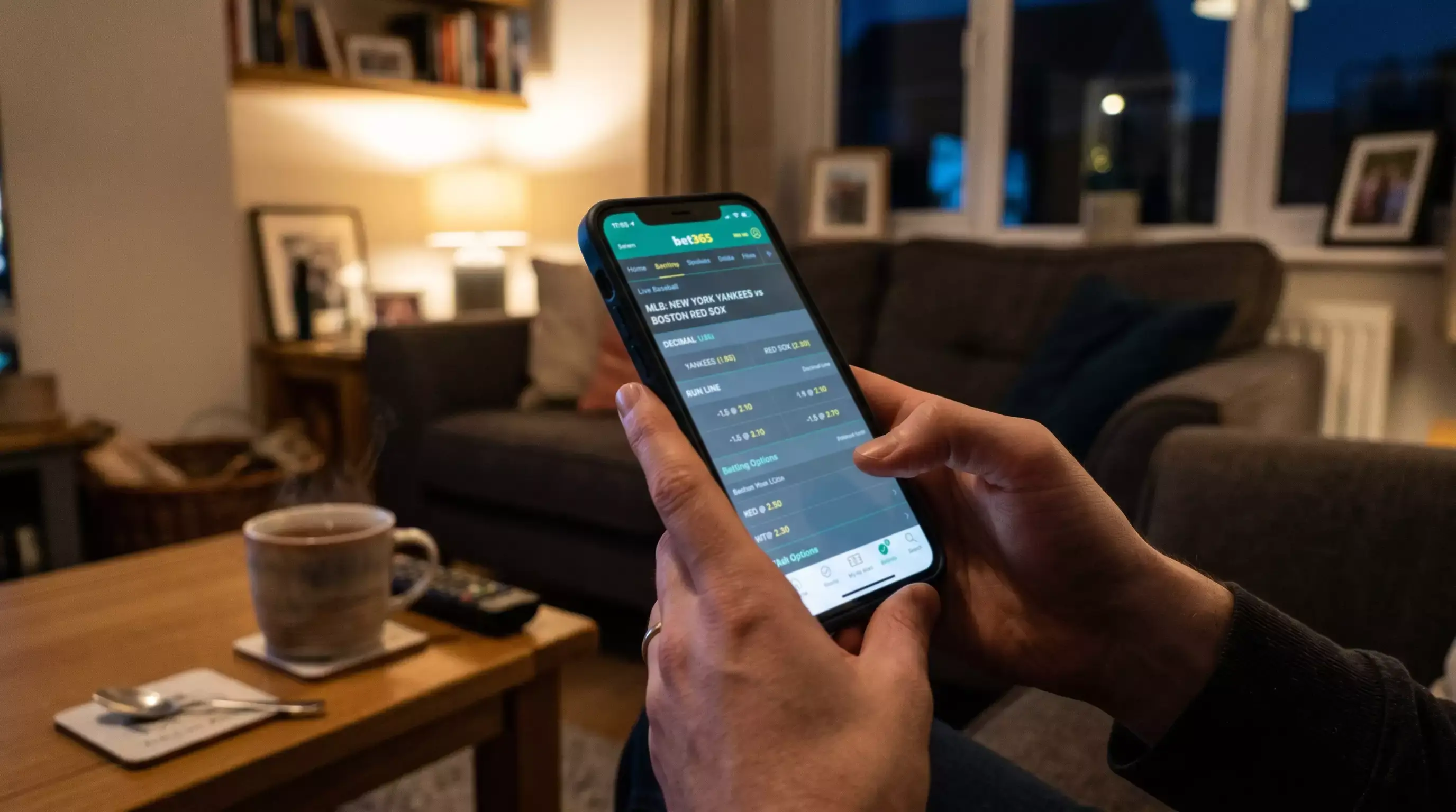 Person holding a smartphone displaying a sportsbook app with baseball odds on screen